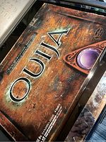Closed box of Ouija board game by Hasbro, showing box art and logo.
