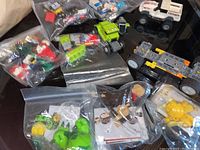 Photo showing assortment of small Lego advent calendar sets, Mega Bloks Pokémon figures, Santa Claus figure missing hat, and several toy vehicles in zippered bags on a table.