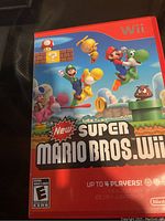 Front cover of New Super Mario Bros. Wii game case for Nintendo Wii showing colorful character artwork and ESRB rating.