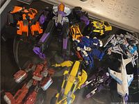 Photo showing several Transformers figures in various colors including orange, purple, black, yellow, red, blue, and white.