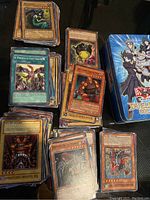 Yu-Gi-Oh cards spread out on surface with notable cards visible and the Duelist Pack Collection tin near them