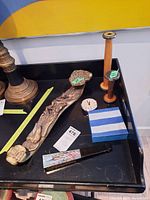 Photo showing the carved jade piece with dragon motifs and sides with Chinese characters, two wooden candlesticks of different heights, small round clock, and decorative hand fan placed on a black surface.