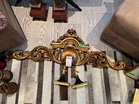 Top down view of large gold leaf carved wood wall sconce showing overall design and two candle holders attached.