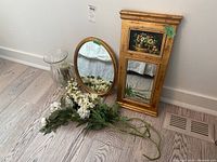 Full lot shot showing both mirrors, the glass vase with candle inside, and scattered faux white lilac flowers on the floor.