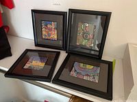 Four framed art prints on white surface, showing overall lot content and condition