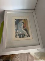 Framed watercolor art print showing a seated nude figure from side and back in muted tones