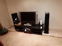 Two black tower speakers positioned on either side of a TV console.