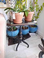 Full side view of wood side table with plants on top and decorative blue pots behind, showing top surface and condition