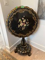 Front view of table upright showing scalloped round top with mother-of-pearl inlays and gilt accents