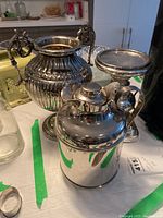 Overview of all three items on table: urn with handles, insulated jug, and candlestick