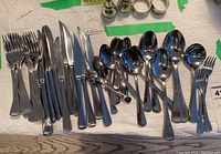 Full set of forks, knives, and spoons laid out on a table showing overall quantity and style.