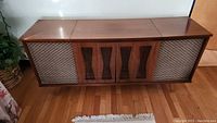 Front view of the closed wood stereo cabinet showing wooden panels and mesh speaker covers.