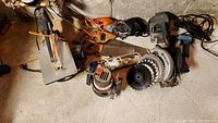 All power tools and hand tools grouped on floor, showing various saws, sanders, and drill.