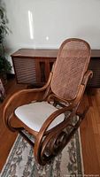Full view of bentwood rocker showing curved wooden frame, seat cushion, and woven cane backrest