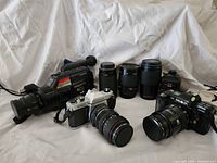 Group shot of Sony Handycam, three telephoto/zoom lenses, Pentax K1000 and Minolta Maxxum 7000 cameras