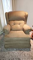 Front view showing light brown cloth fabric upholstery, wingback design, tufted seat and back cushions