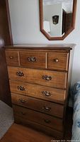 Full front view of the tall dresser showing the five drawers with original hardware and wood finish.