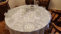 Photo showing full assortment of cut glass servingware on a round table, including platters, bowls, and shakers