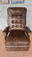 Front view of brown vinyl recliner chair with tufted backrest and wooden armrests.