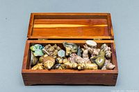 Open wooden box containing multiple small ceramic animal figurines, showing variety and quantity of items in lot.