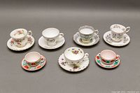 All five teacup and saucer sets presented in a row showing variety in floral patterns and demitasse sizes