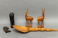 Full view of all five wooden tribal carvings including the wall hanging spoon, pair of impalas, and two smaller carvings.