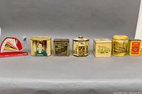 Wide shot showing all six tins and the Jiffy-Way egg scale on gray background.