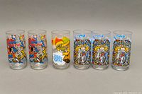 Six glass tumblers lined up on a table showing colorful character designs from Peter Pan, The Muppets and Miss Piggy riding a motorcycle.