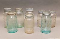 All eight glass mason jars displayed standing with lids on, showing assortment of colors and general condition.