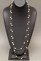 Full view of the long silver lariat necklace displayed on black bust showing pearl placement and chain style.