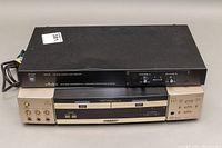 Photo shows both units stacked: Audpro black wireless microphone receiver resting on top of Sharp beige DVD/CD player, front view.