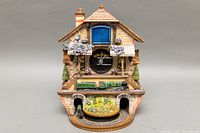 Front view of the Flying Scotsman Flying Scotsman train model on the track below the clock face of the building-shaped cuckoo clock.