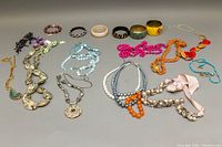 Wide shot of all bracelets and necklaces arranged on a surface, showing variety of styles and colors
