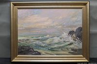 Frontal view of the framed oil painting showing seascape scene with crashing waves and rocky shoreline.
