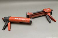 Two HILTI dispensing tools showing general wear and tear, placed side by side for scale and comparison.