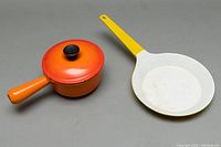 Orange cast iron sauce pot and yellow skillet side by side showing size difference and exterior colors