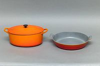 Front view of oval covered casserole with lid (left) and paella pan (right)