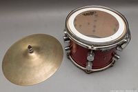 Photo showing red Pacific snare drum with chrome hardware and 14-inch cymbal