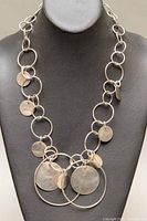 Front view of the retro silver necklace displaying linked circular rings with attached flat discs against a black bust.