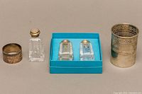 All items displayed together: sterling silver cup holder, one salt shaker, two shaker set in blue box