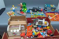 Main view of the assortment showing the toys in and outside the box including figurines, kaleidoscopes, puzzles, games and vehicles.