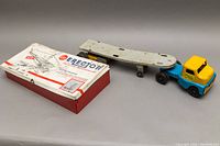 LINCOLNS Husky tin truck with trailer, and GILBERT Erector Set tin box side by side on gray background.