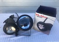Two black spotlights shown side by side, one PS-46sw Superspot with box and stand and the other an American DJ PL-1000 with clamp