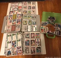 Photo showing three binders filled with baseball cards and a green plastic case containing loose cards