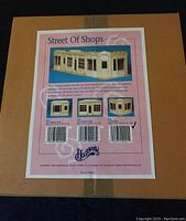 Image of the box with the Street of Shops label and assembly options showing the corner shop model in wood.