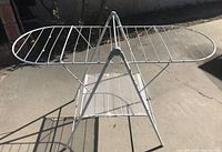 Front view of the white metal folding drying rack open with wings extended and lower mesh rack visible.