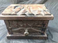 Front view of hand carved wood box showing elephant design and drawer with wooden knob.
