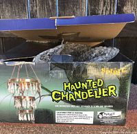 Spirit Halloween Haunted Chandelier box with branding and warnings, showing 3-tiered chandelier image