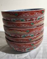 Stacked view showing red exterior with orange and green flower and geometric patterns on all five bowls