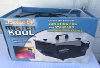 Box showing American DJ Mister Kool branding and effect description for low-lying fog using fog fluid and ice cubes.